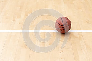 Orange basketball ball on hardwood court floor