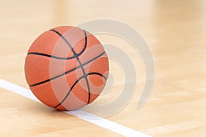 Orange basketball ball on hardwood court floor