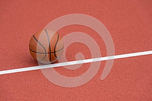 Orange basketball on brown court of gymnasium sport floor. Street basketball concept