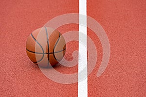 Orange basketball on brown court of gymnasium sport floor. Street basketball concept