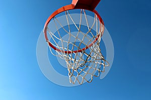 Orange basketball rim hoop and white net against blue sky