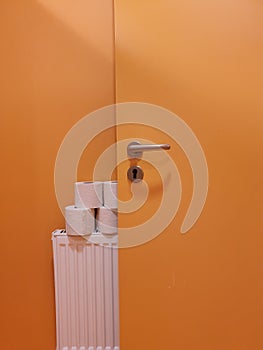 Orange bathroom door near a heater with toilet paper