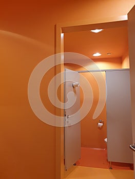 Orange bathroom interior with stalls