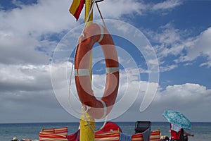Orange beach lifebuoy on the background of clouds and sky