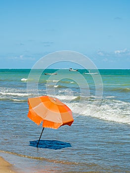 Orange beach umbrella near the shorebreak