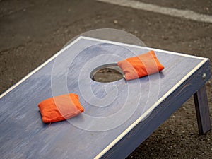 Orange beanbags sitting on blue cornhole board platform