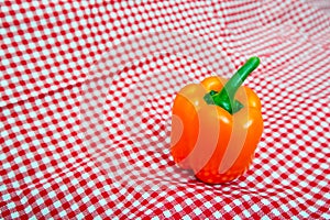 Orange Bell Pepper against red and white chequered cloth