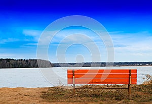 Orange bench on river beach horizon background