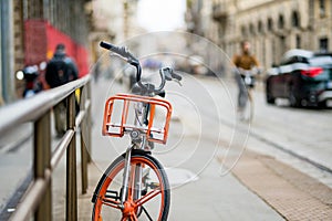 Orange bicycle parked on the street of Milan. Exploring an old town. Milan, Italy