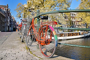 Orange bike with LGBT flag parked on a bridge in Amsterdam, Netherlands