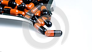 Orange-black capsule pills on drug tray. Antibiotics drug resistance. Drug use with reasonable. Antimicrobial capsule pills. photo