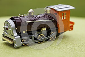 An orange and black toy train on a green background