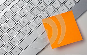 Blank sticky note pasted on keyboard at work table