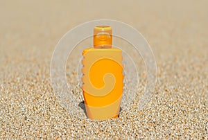 Orange blank sun screen bottle with space for copy isolated on a sea sand beach background, soft focus