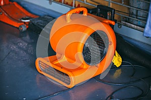 Orange blower fan machine on wet floor. Heavy Duty Industrial Portable Blower Fan on floor  Used to reduce heat to racing cars.