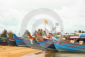 orange and blue fishing boats lined up in a harbor