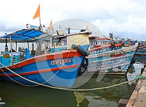 orange and blue fishing motor boats lined up in a fishing sea harbor