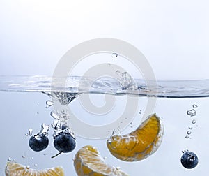 Orange and Blueberries Splashing into Water