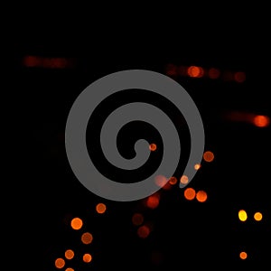 Orange bokeh on a black background  burning and blurred sparks from the fire. Particles of burning embers fly and glow isolated in