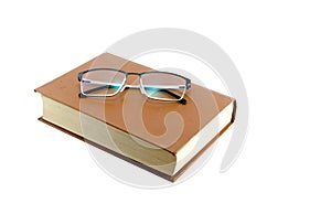 Orange book isolated on white background and glasses on top.