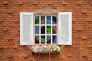 Orange brick wall and white wood window with colorful flowers