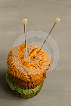 Orange, brown, green and marsh woolen yarn and knitting needles