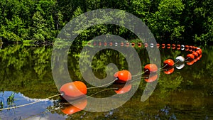 Orange buoys with reflection in river in springtime