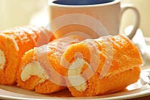 Orange cake roll stuffed cream eat couple with coffee on dish