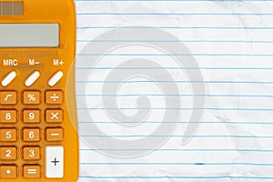 Orange calculator on wrinkled lined paper background