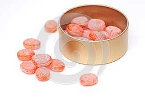 Orange candies in tin jar on white background