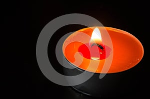 Orange candle burning on a black background