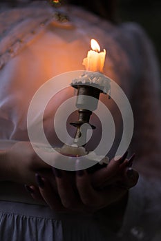 Orange candle in a candlestick and hold her hands