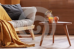 Orange candle on wooden coffee table in cozy living room interior