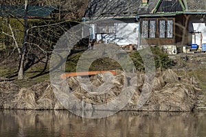 Orange canoe among withered grass on riverbank