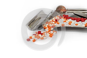 Orange capsules pills and drug tray on white background with cop