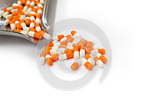 Orange capsules pills and drug tray on white background with copy space