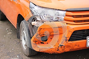 An orange car has an accident while traveling.