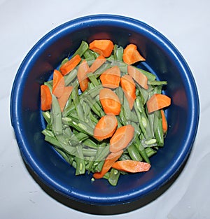 The orange carrot and green bean in the bowl. Top view with white background