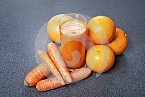 Orange and carrot juice in glass with ginger, fresh vegetables