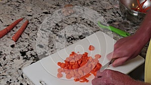 Orange Carrots Being Chopped on a White Plastic Cutting Board