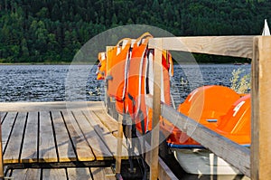 Orange catamarans on lake moored at the pier. Pleasure boats with life jackets