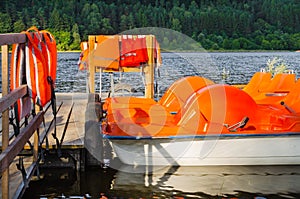 Orange catamarans on lake moored at the pier. Pleasure boats with life jackets.