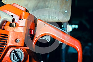 Orange chainsaw close-up. Gasoline tool controls, off button and gas pedal. Filler neck of the tank for the fuel mixture