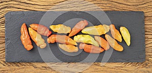 Orange cheiro peppers on a stone board over wooden table. Typical brazilian ingredient photo