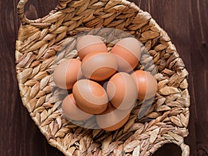 Orange chicken eggs in a wicker basket on a wooden background. Easter concept. Minimalism. Top view