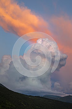 Orange cirro-cumulus and cumulus clouds in the evening light at sunset in the mountains photo