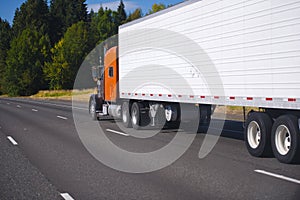 Orange classic semi truck and trailer on highway