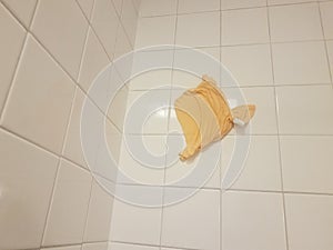 Orange cloth or rag stuck on bathroom tiles