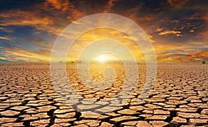 Orange cloudy sunset over cracked desert