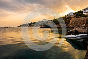 Orange cloudy sunset view in Finikas Port Siros Island with dinghy boat parked at the pier and sailing boats in the background. photo